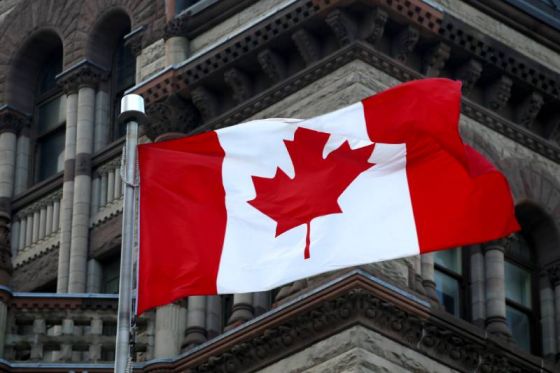 Canadian flag on a pole next to an old building